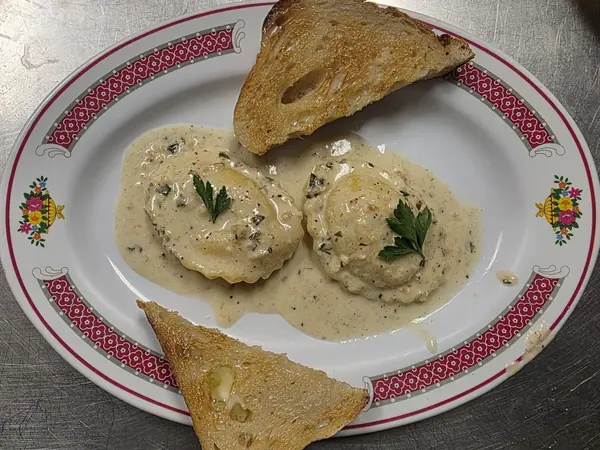 Two large ravioli in a herbed cream sauce, plated with toasted bread.
